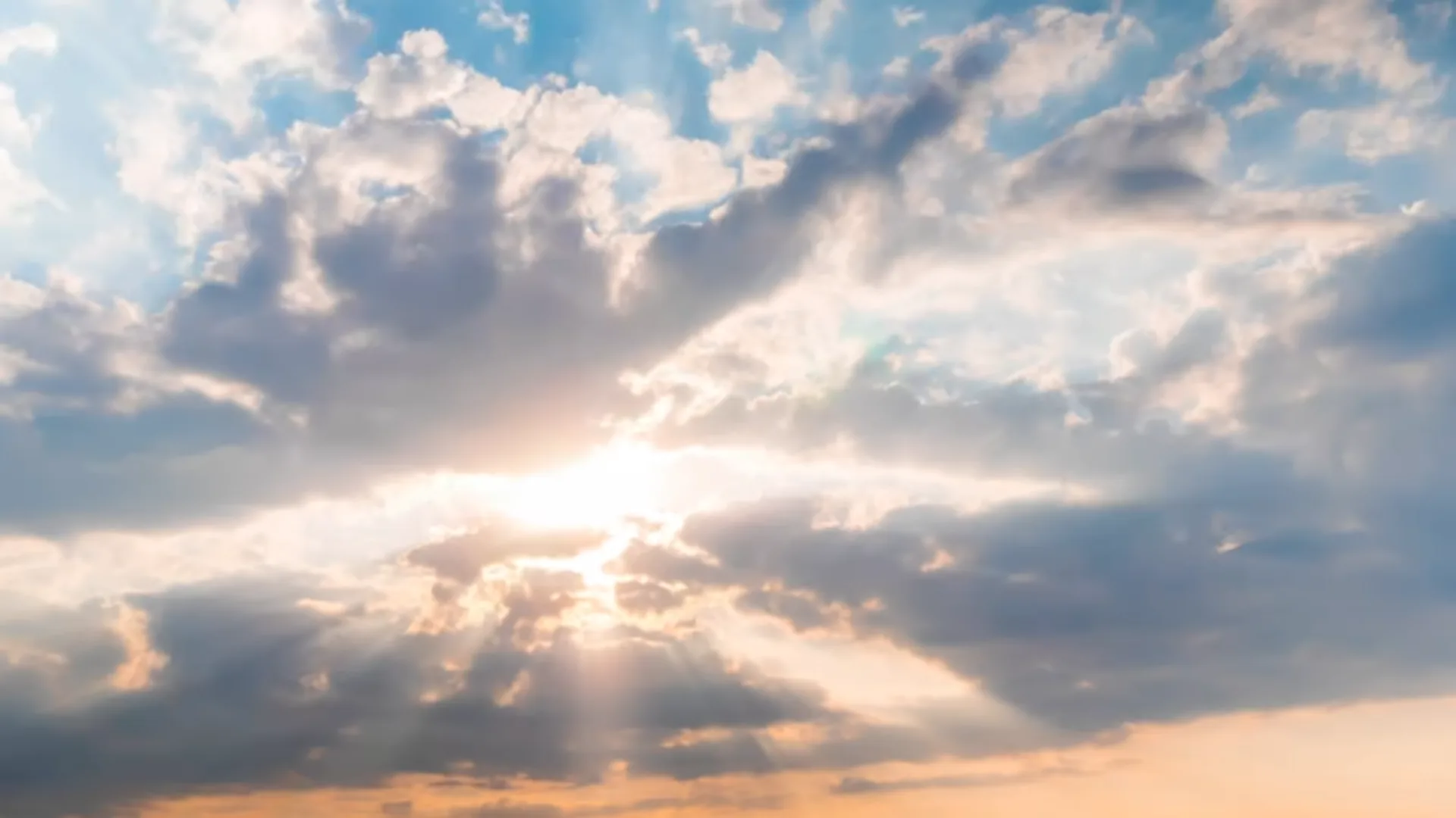 Weiter Himmel mit aufgelockerter Wolkendecke, durch die Sonnenlicht fällt — ruhig und offen, ohne Personen.